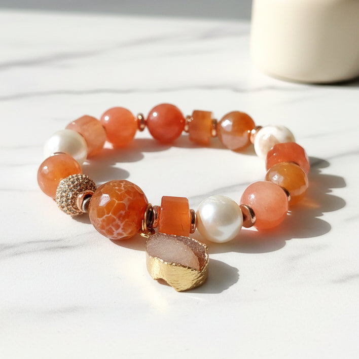 A multicolored beaded bracelet with a gold-tone charm, featuring a mix of apricot and peach colored beads.