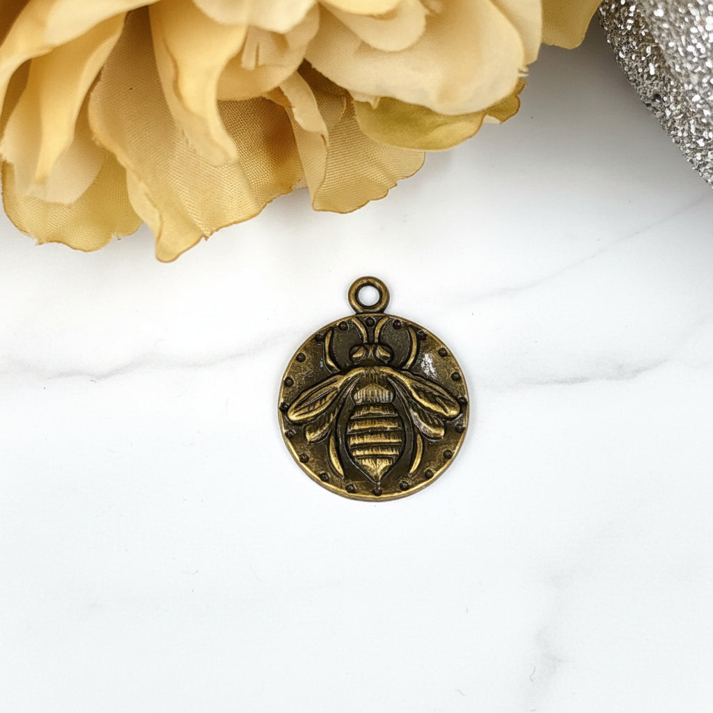 A bronze bee-shaped pendant or charm.