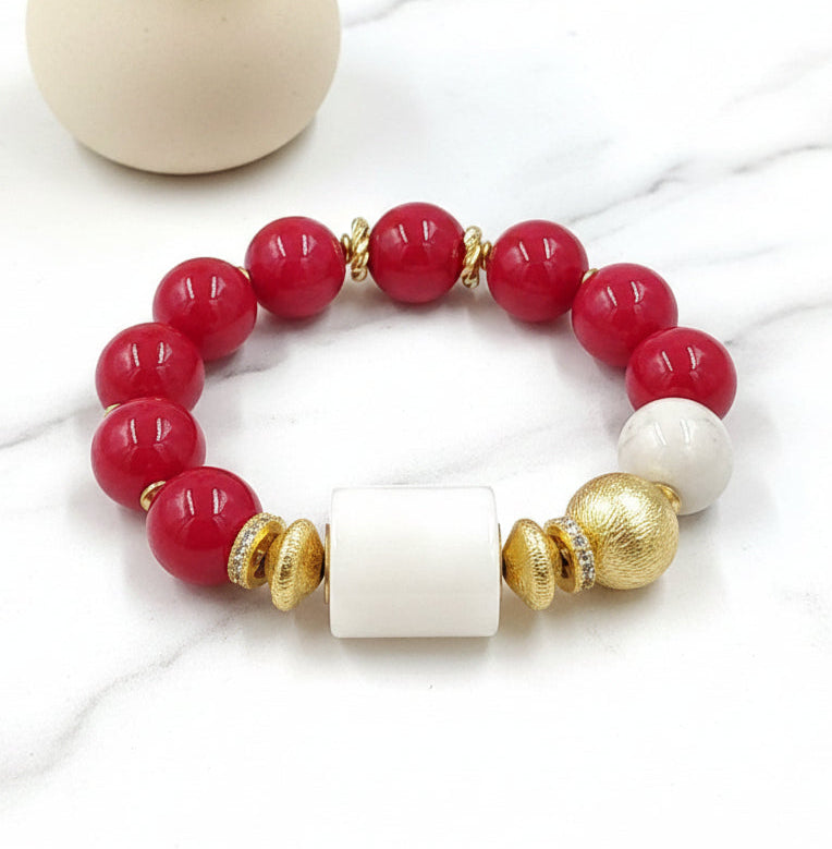 A multicolored beaded bracelet with red, white, and gold colors, and a lemon yellow accent.