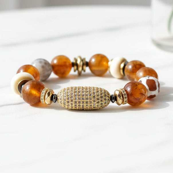 A multicolored beaded bracelet with a gold-colored pave centerpiece, displayed on a neutral background