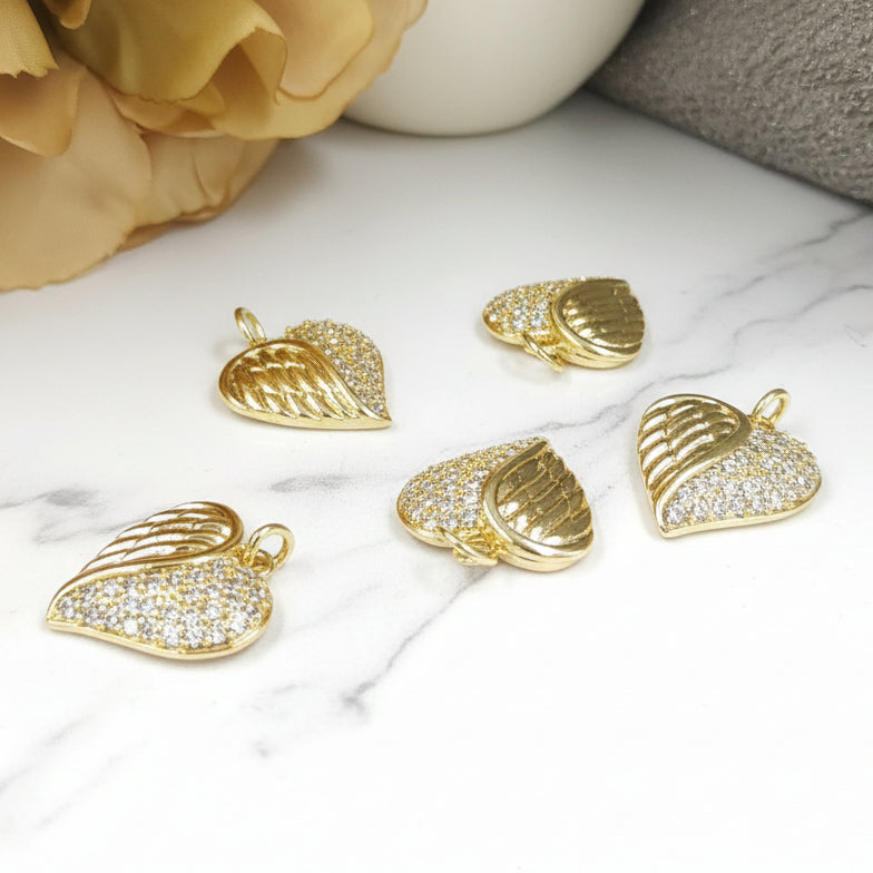 Gold heart-shaped pendants with clear stones on a white surface.