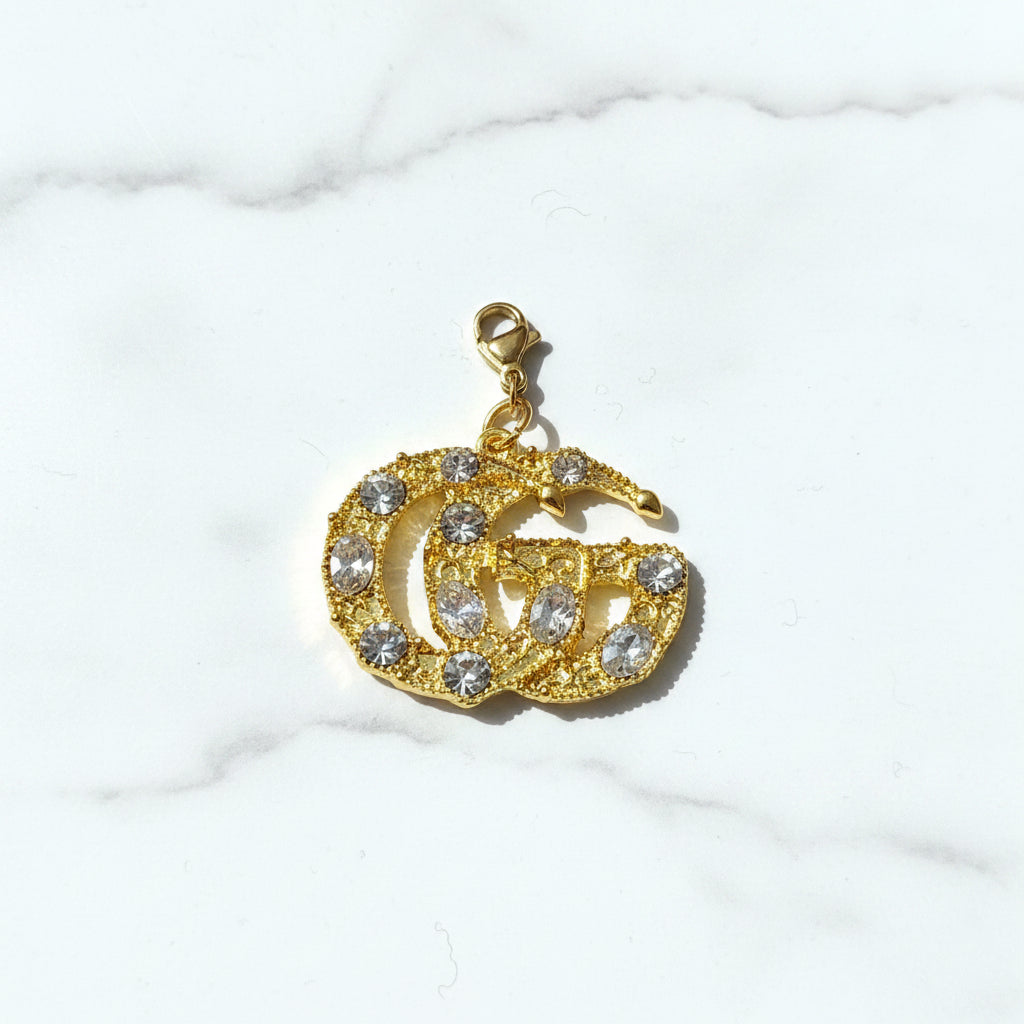 A Gucci inspired branded gold-colored charm with diamonds, designed in the shape of the GG logo.
