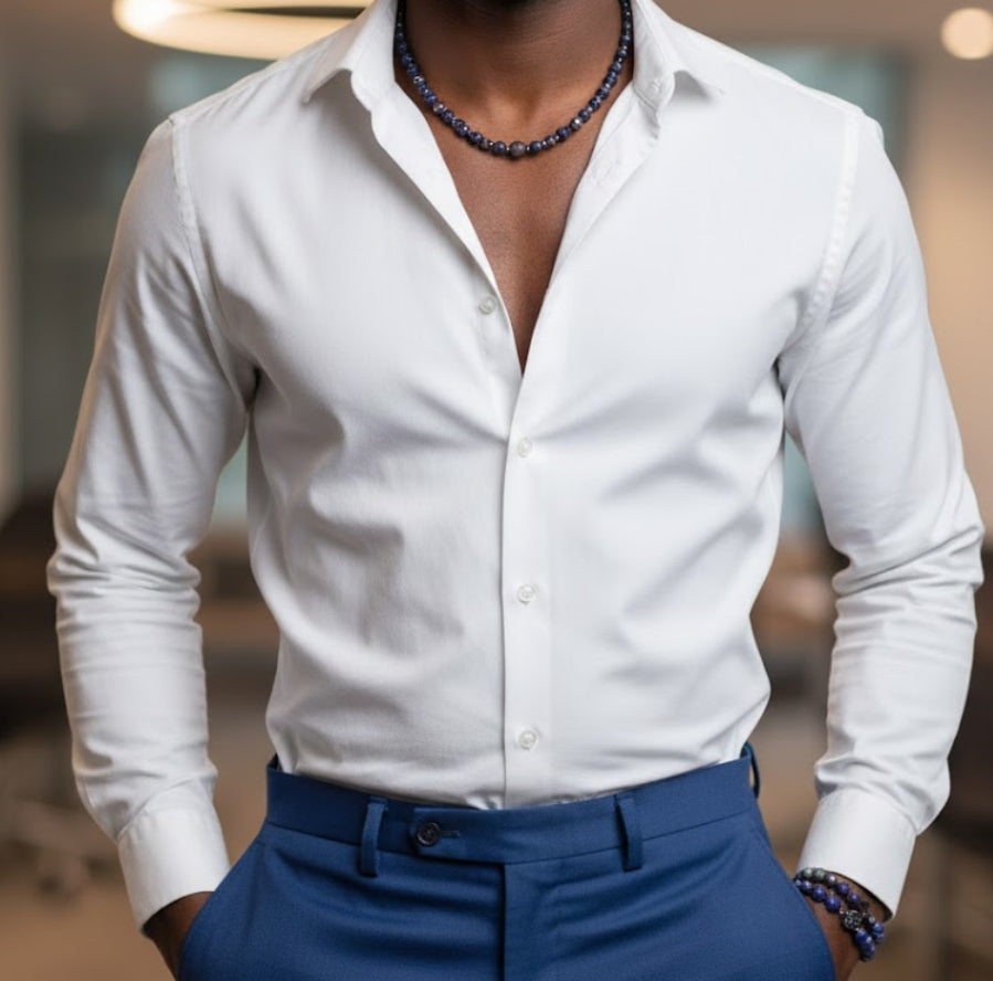 Person wearing a white dress shirt and blue pants and a blue lapis necklace and bracelet set with a blurred background