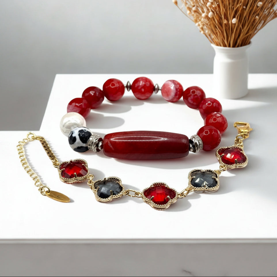 Two piece bracelet set with red and black beads on a white surface.