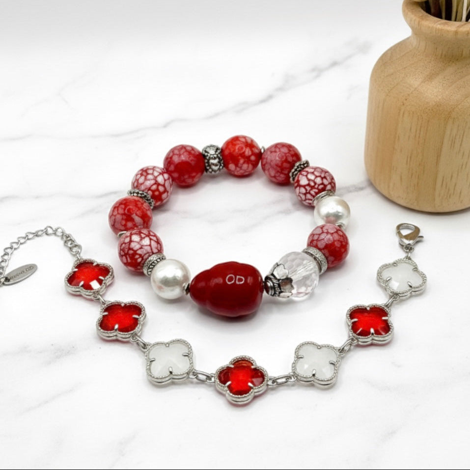 Beaded bracelet with red and white beads on a white surface with a wooden vase in the background.