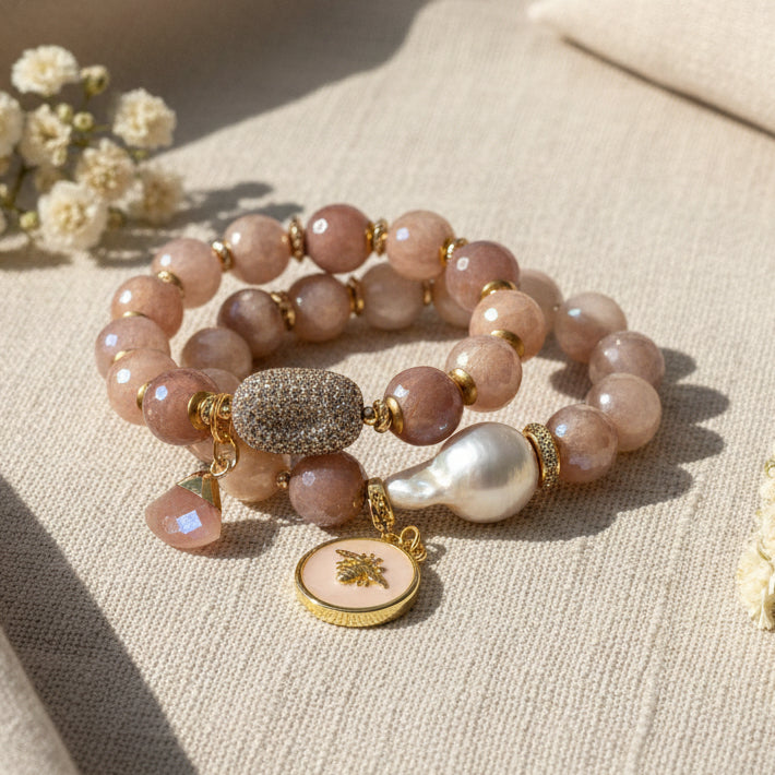 Beaded bracelet with gold accents and charms on a white background