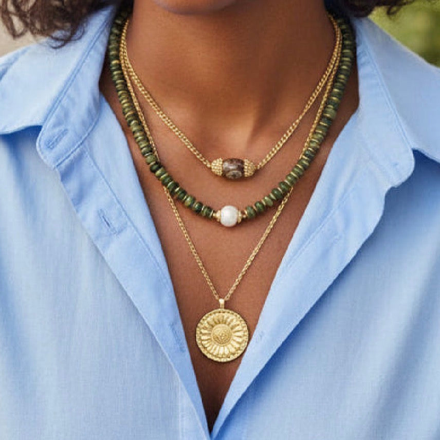 Person wearing multiple necklaces with a blue shirt