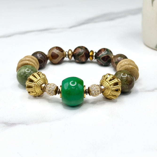 A bracelet with gold-colored metal beads and one large green turquoise bead, displayed against a neutral background.