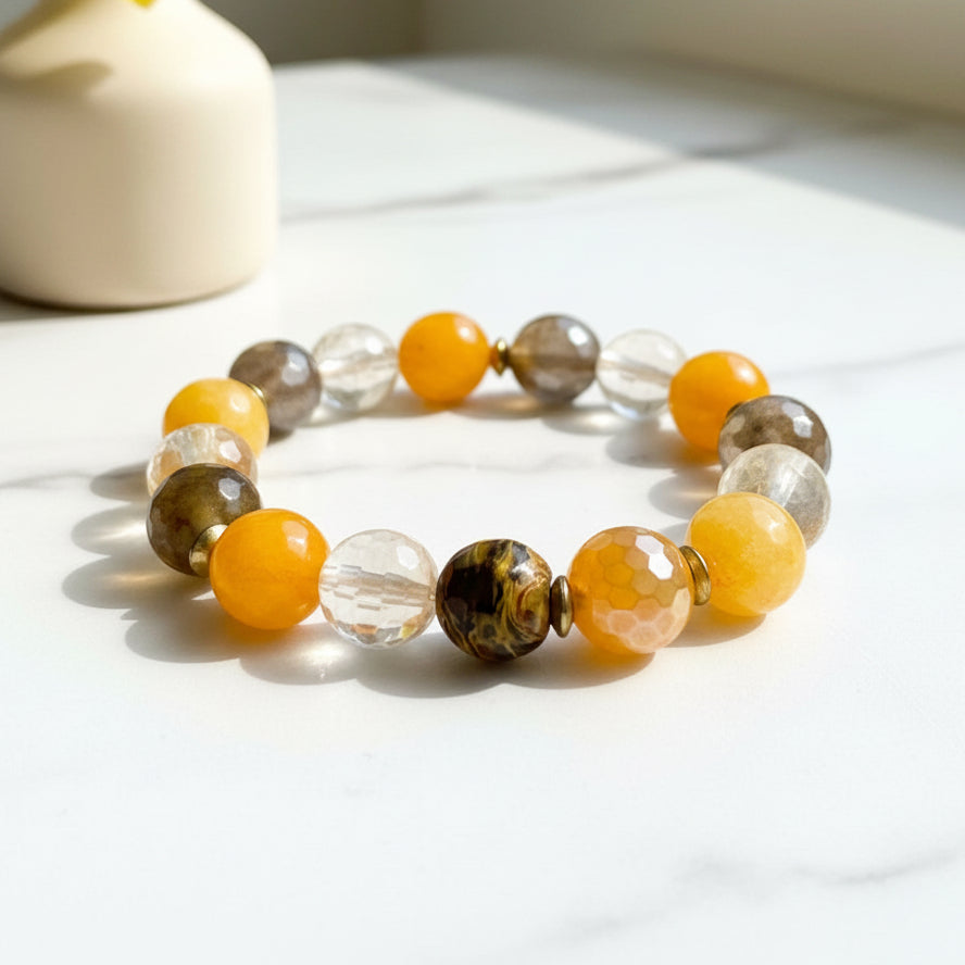 A bracelet with multicolored beads, featuring shades of yellow, brown, and clear, displayed on a neutral background.