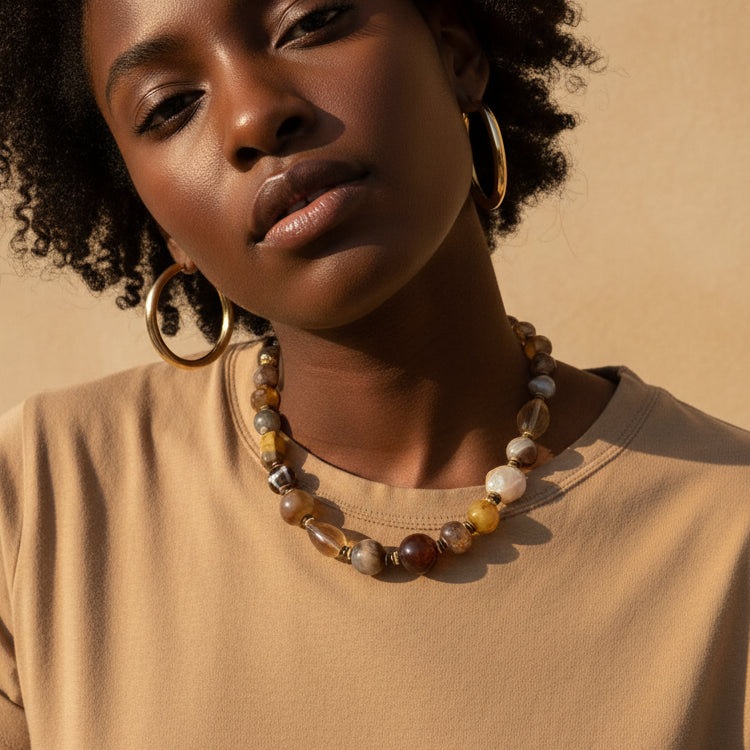 Necklace with multicolored beads worn by a person wearing a tan shirt.