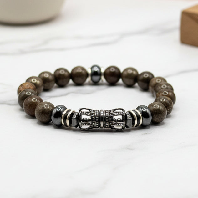 Beaded bracelet with a metal crown centerpiece on a white surface