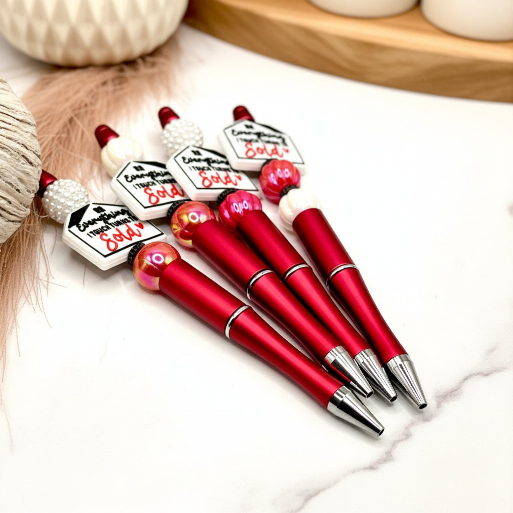 A collection of pens with red bodies and silver accents, with some sort of label on the top. The pens are displayed against a white background with a textured object to the left.