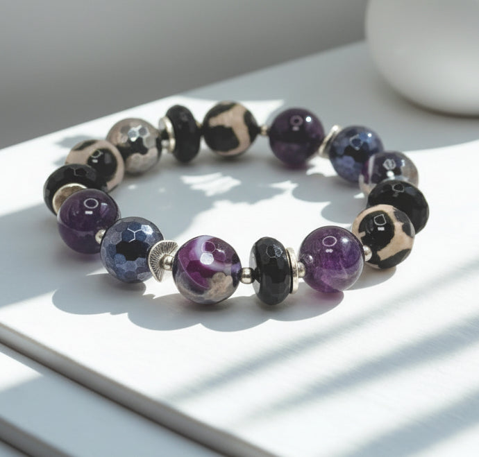 Beaded bracelet with purple and black beads on a white surface