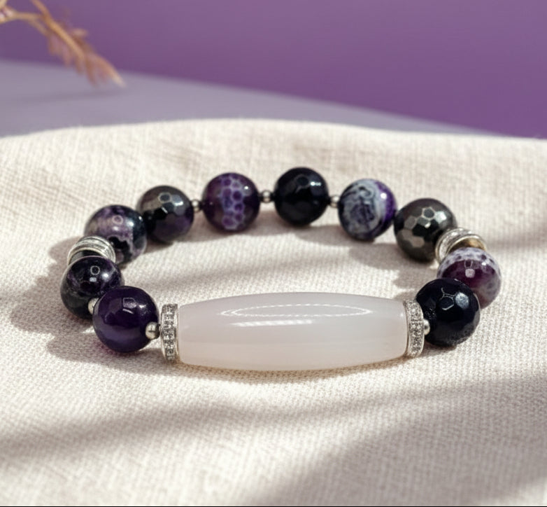 Beaded bracelet with a central white stone on a white surface with a purple background