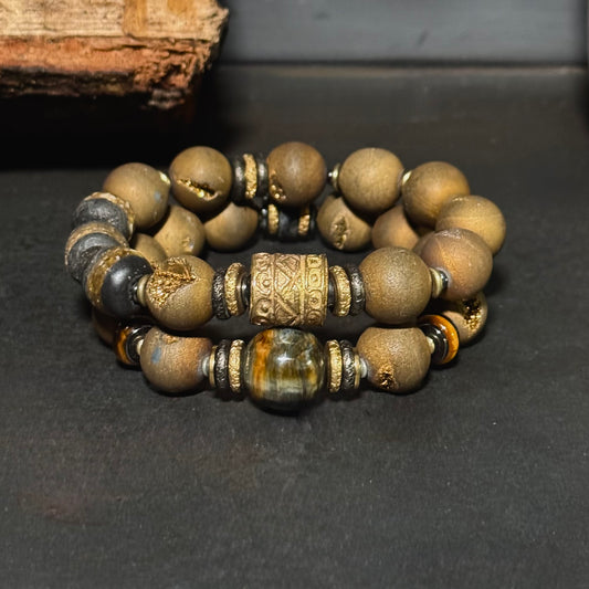 Stack of beaded bracelets with gold and black accents on a dark surface