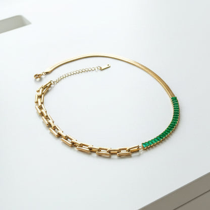 18k gold plated link and herringbone necklace with emerald green baguettes on a white surface
