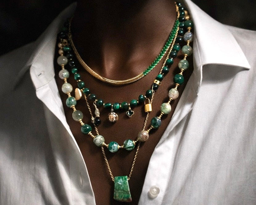 Person wearing a white shirt with a layered  beaded and chain necklaces.