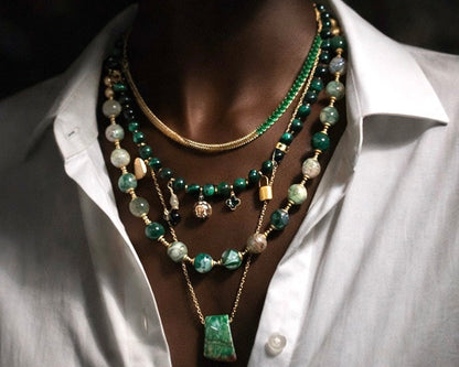 Person wearing a white shirt with a layered  beaded and chain necklaces.