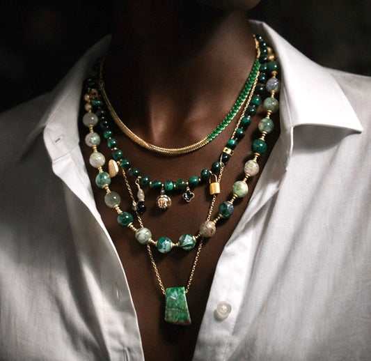 Person wearing a white shirt with a layered  beaded and chain necklaces.