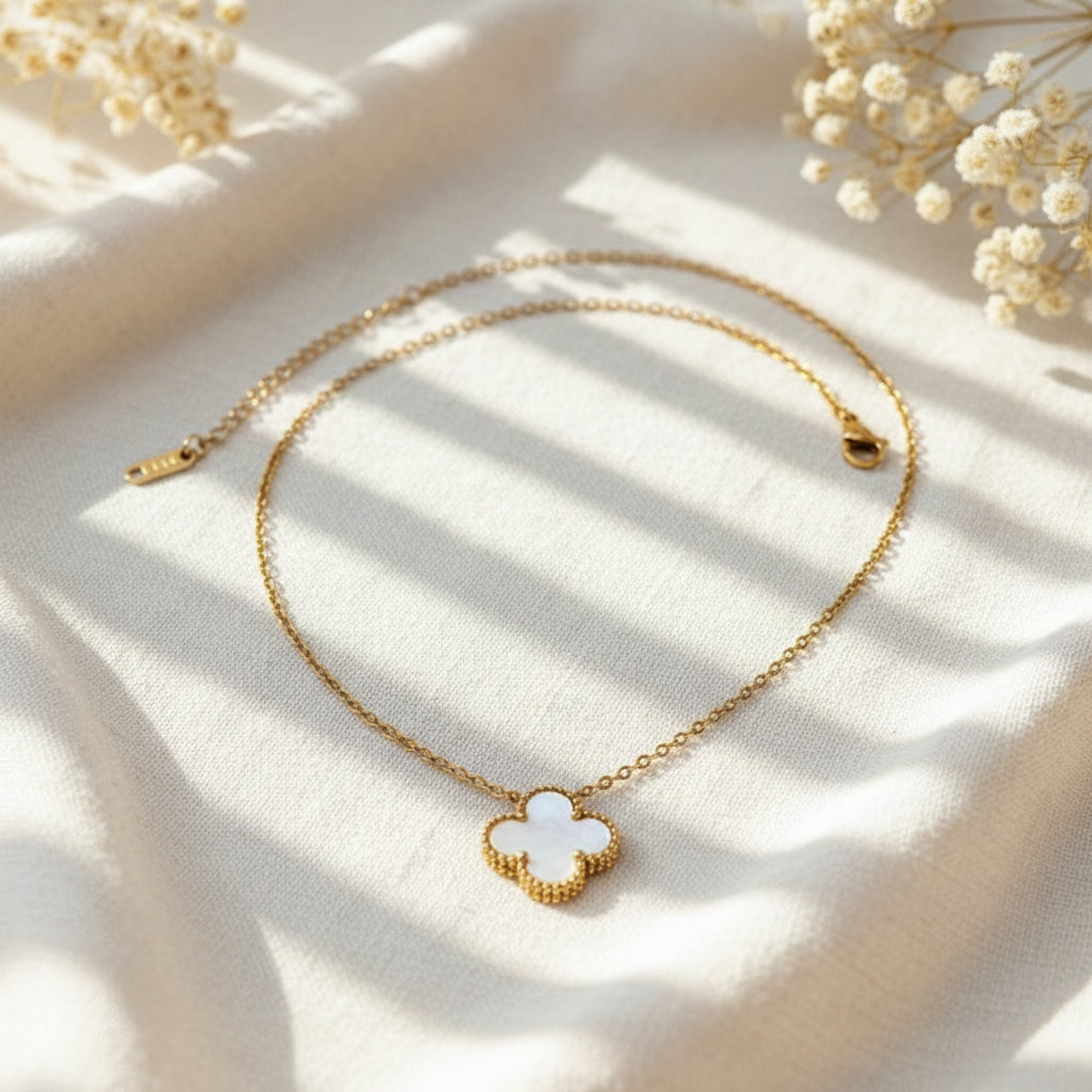 Gold necklace with a clover-shaped pendant on a light background