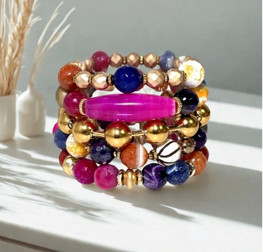 Stack of colorful beaded bracelets on a white surface with a neutral background