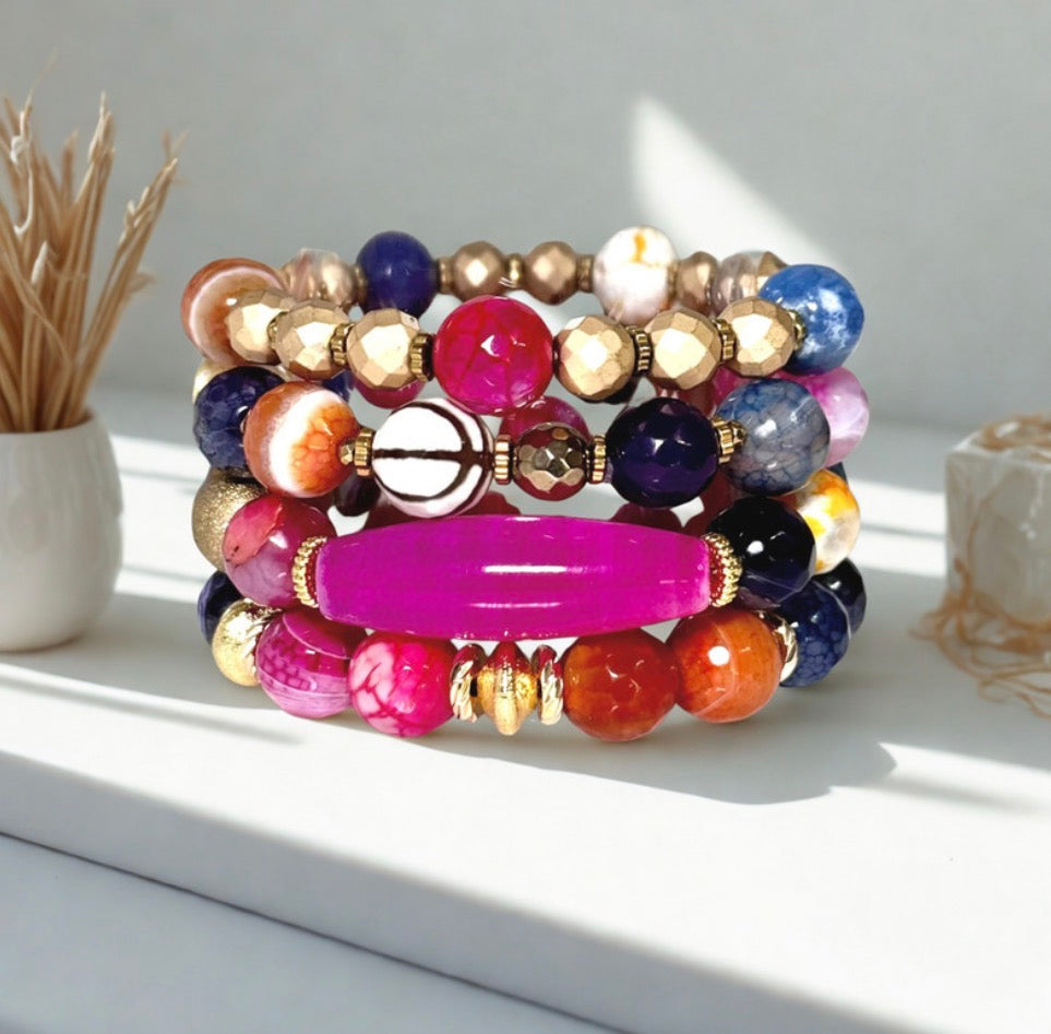 Stack of colorful agate beaded bracelets on a white surface.