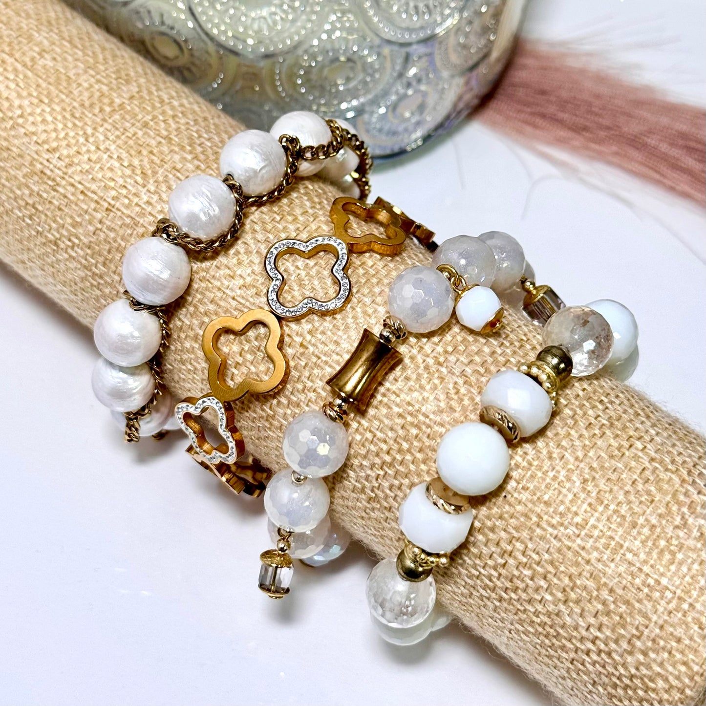 Bracelet with white beads and gold charms on a beige fabric background