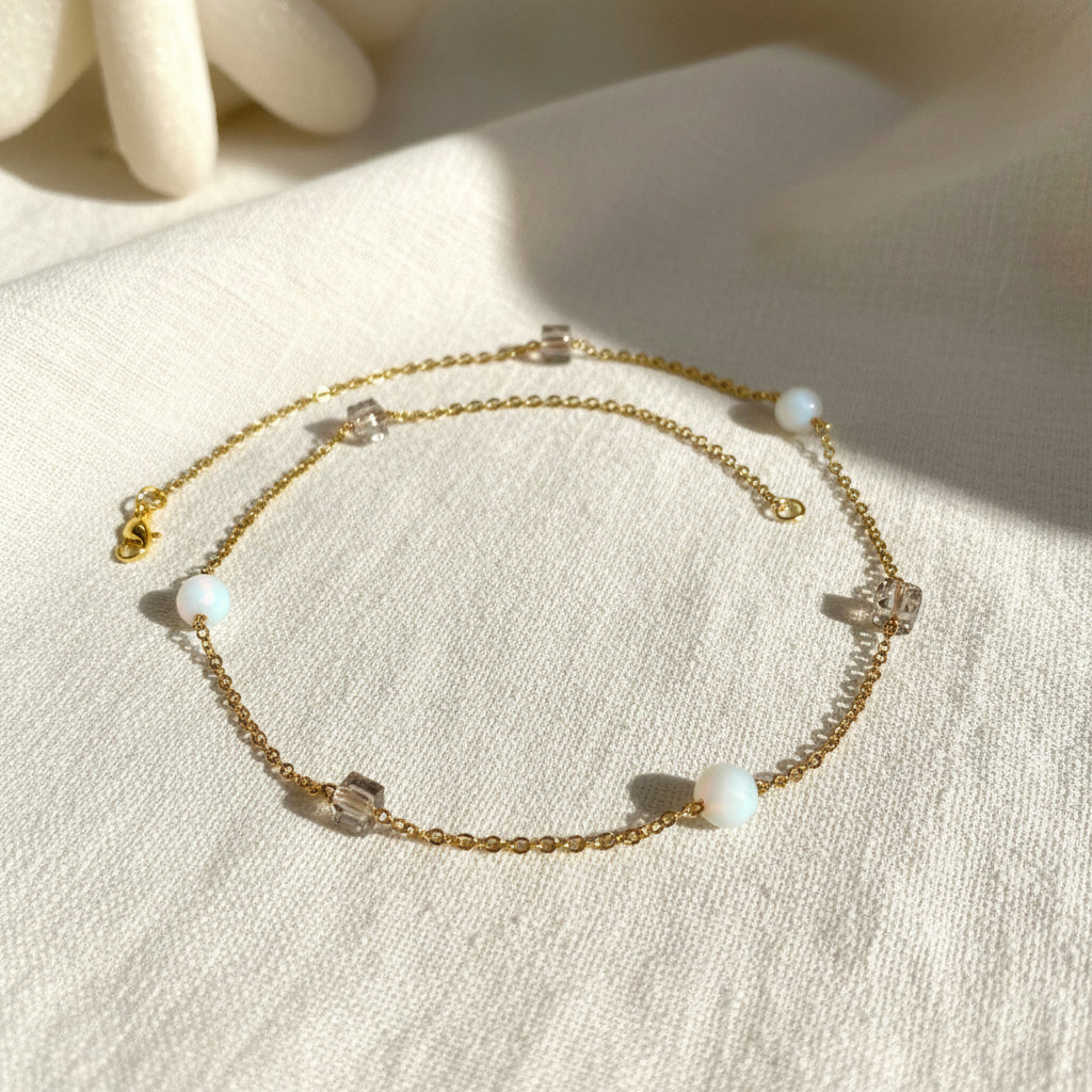 Gold chain bracelet with pearls on a white surface