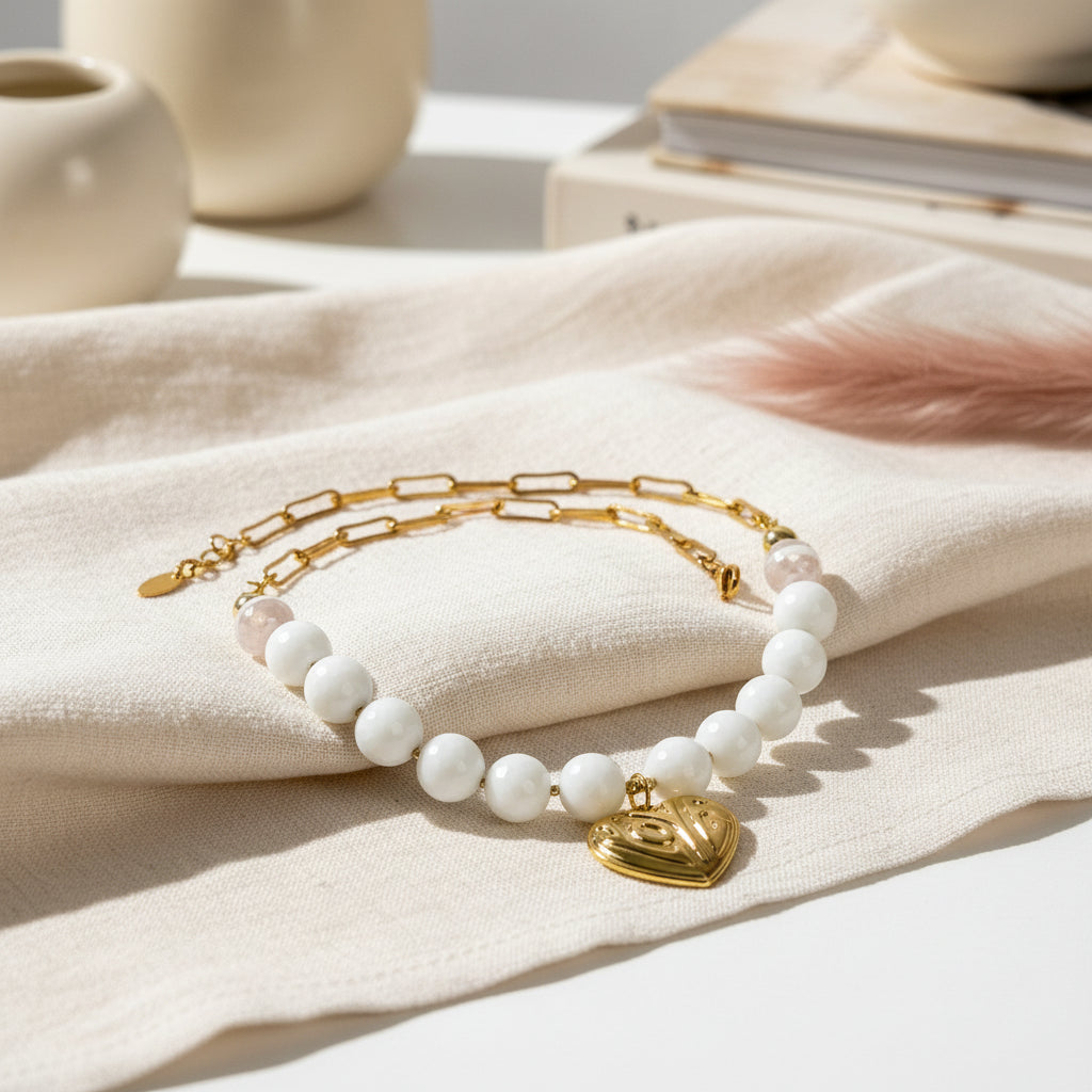 Bracelet with white beads and gold heart charm on a white background