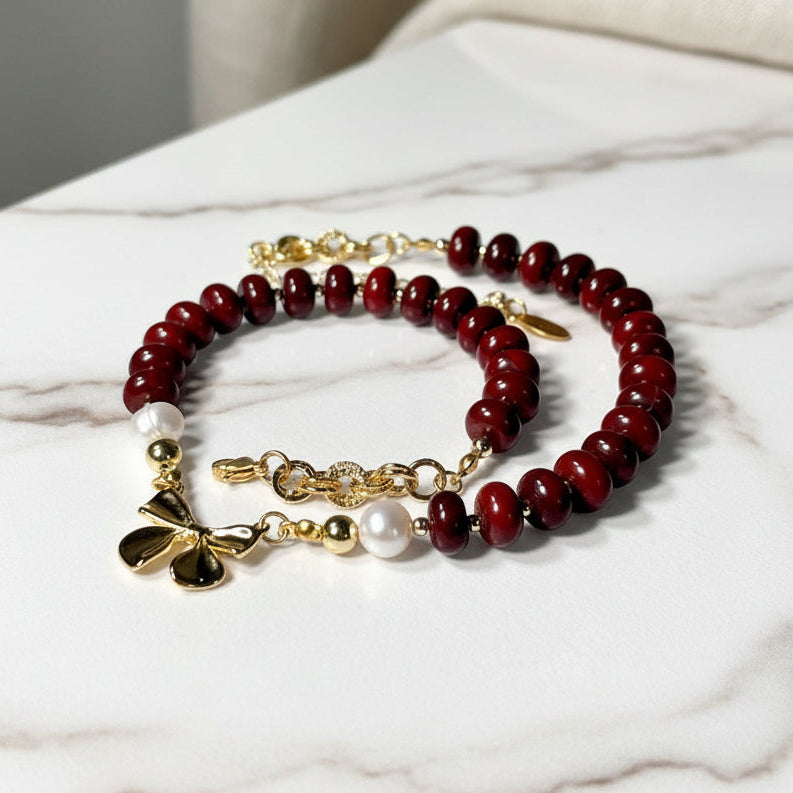 Beaded necklace with red jasper beads, gold accents, and pearl elements on a white background