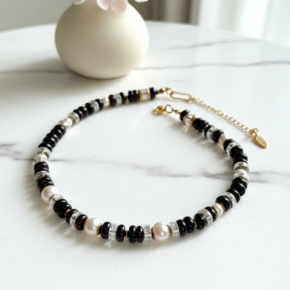 Necklace with garnet, fresh water pearl, and gold beads on a white background