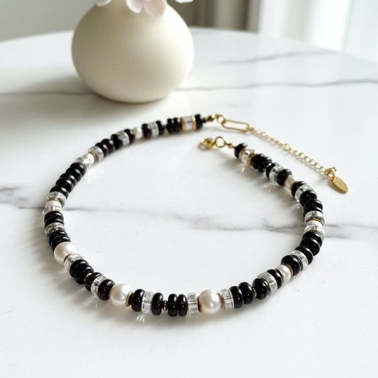 Necklace with garnet, fresh water pearl, and gold beads on a white background