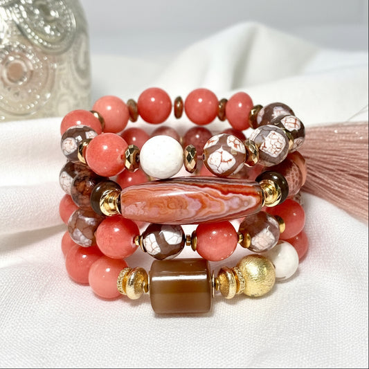 Stack of beaded bracelets with peach, gold, and brown beads on a white surface.