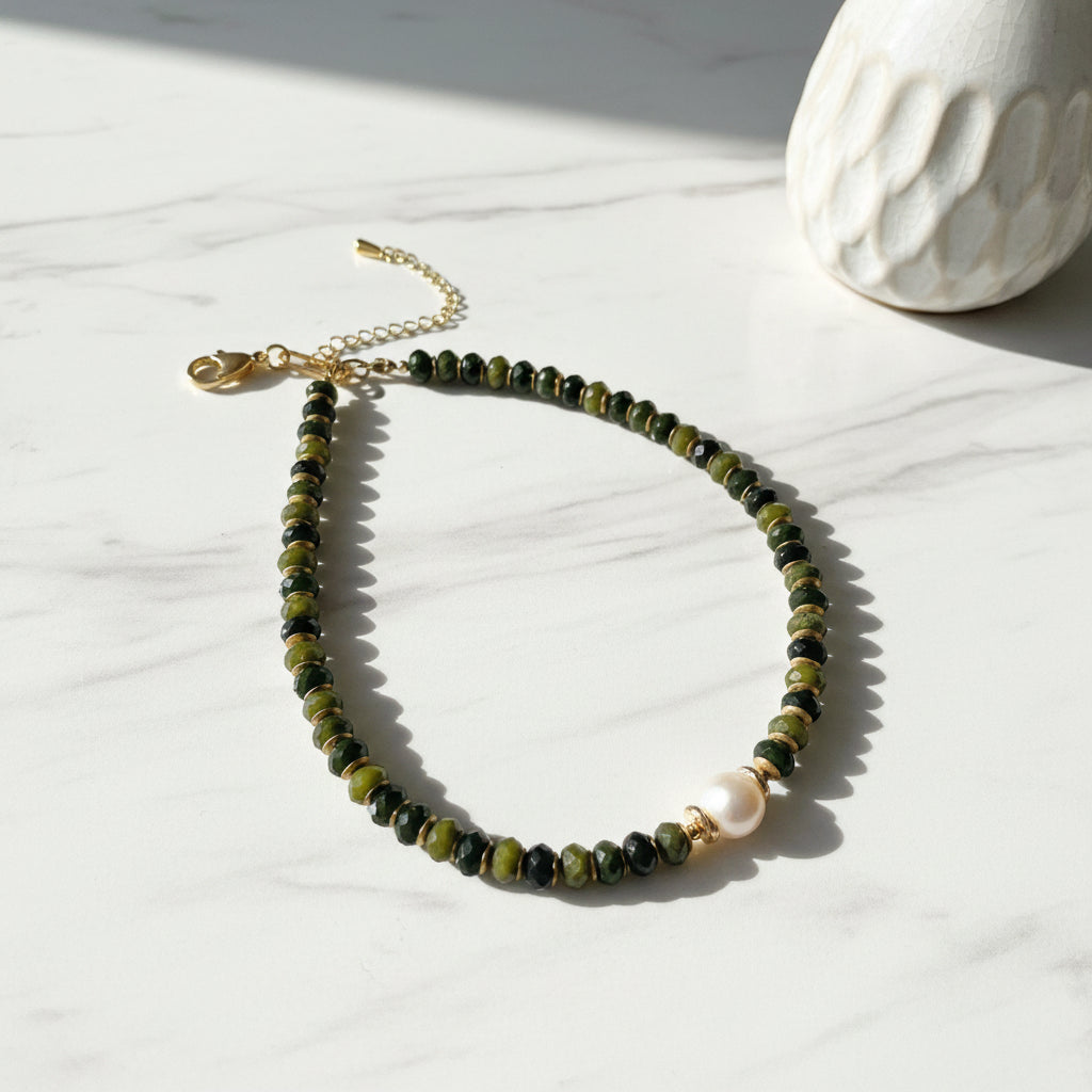 Necklace with green beads and a pearl on a white background