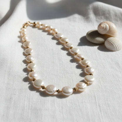 Coin pearl necklace with gold beads on a white background