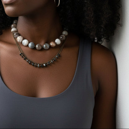 Necklace with large beads worn by a person in a gray tank.