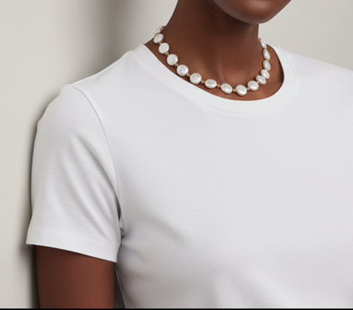 Coin pearl necklace on a black female model against a plain background