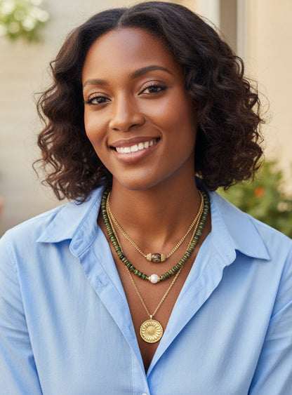 Woman wearing a light blue shirt and multiple necklaces outdoors
