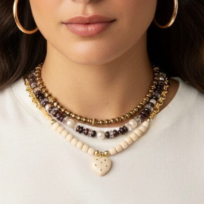 Close-up of a woman wearing multiple necklaces with a plain background
