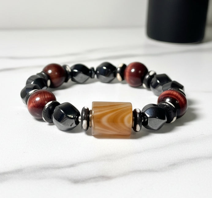 Beaded bracelet with brown, black, and beige beads on a white background