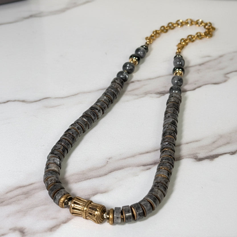 Necklace with gray beads and gold accents on a white surface