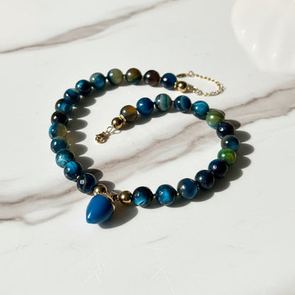 Beaded necklace with blue and green beads on a white surface