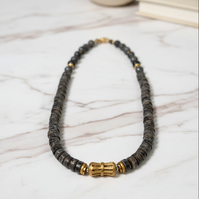 Necklace with dark beads and gold accents on a white background