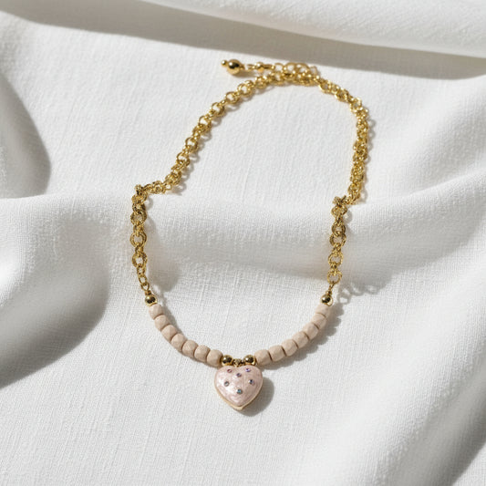 Necklace with heart-shaped pendant and beige beads on a white background