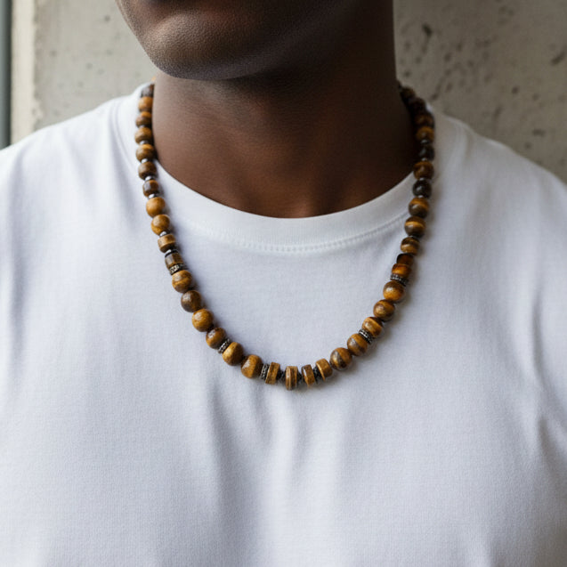 Necklace with brown and gold beads on a black stand against a white background