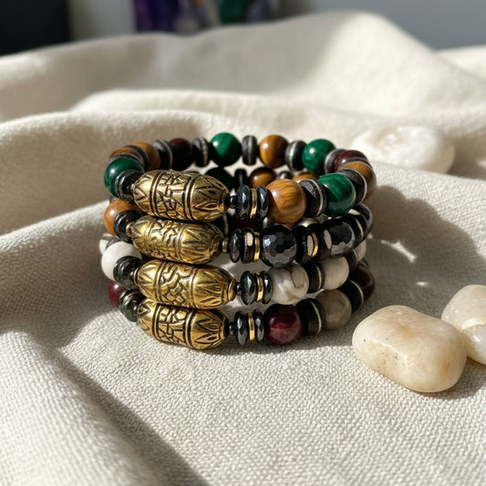Stack of beaded bracelets with metal accents on a white surface