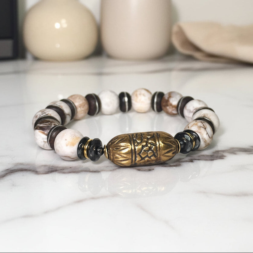 Beaded bracelet with a large decorative gold bead on a white surface