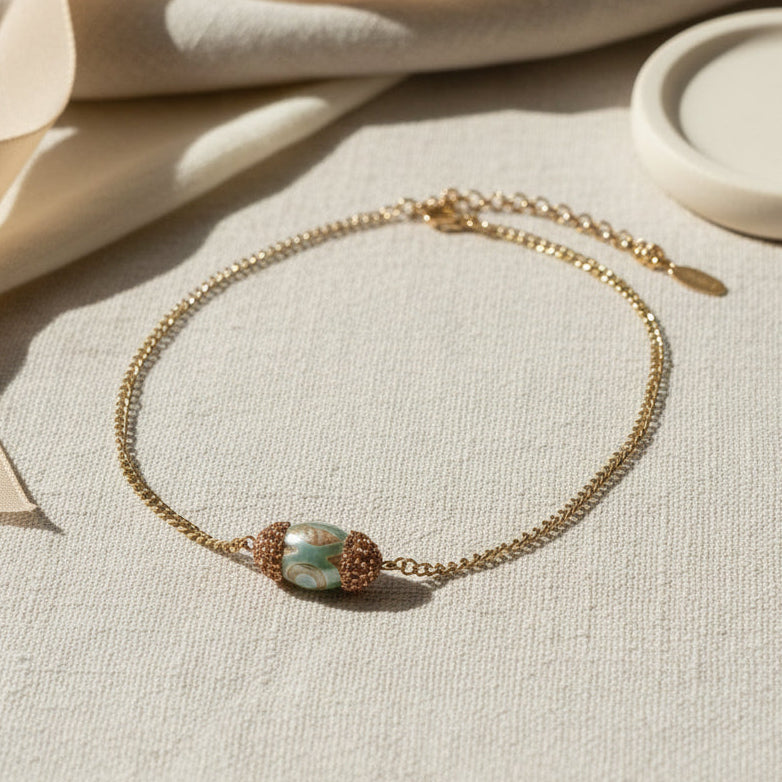 Gold chain bracelet with a decorative clasp on a white background