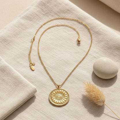 Gold necklace with a decorative pendant on a white background