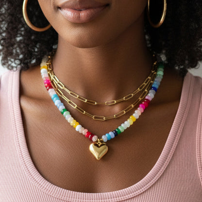 Colorful beaded necklace with a gold heart pendant on a black model.